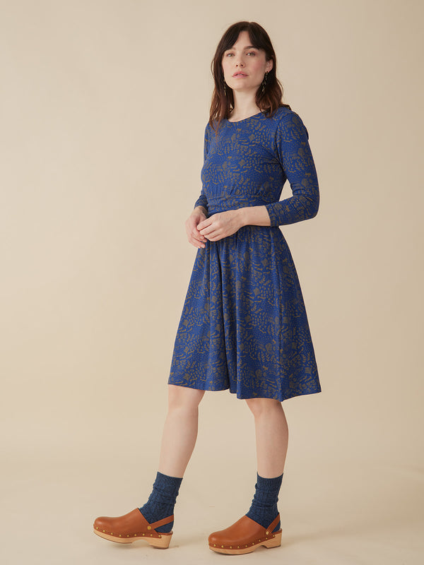 Woman wearing a blue patterned dress on a beige background