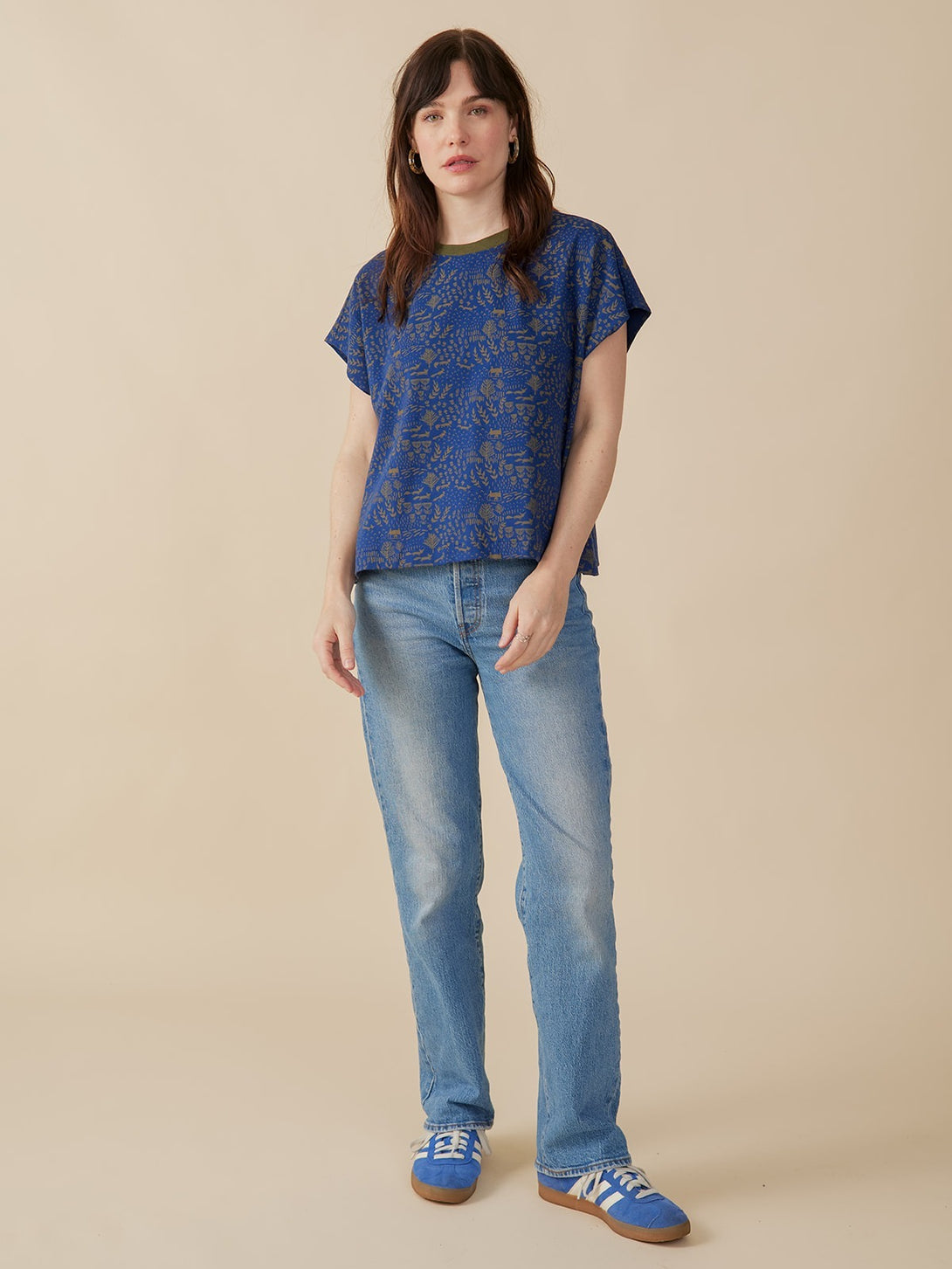 Woman wearing a blue patterned fox print  top and jeans on a beige background