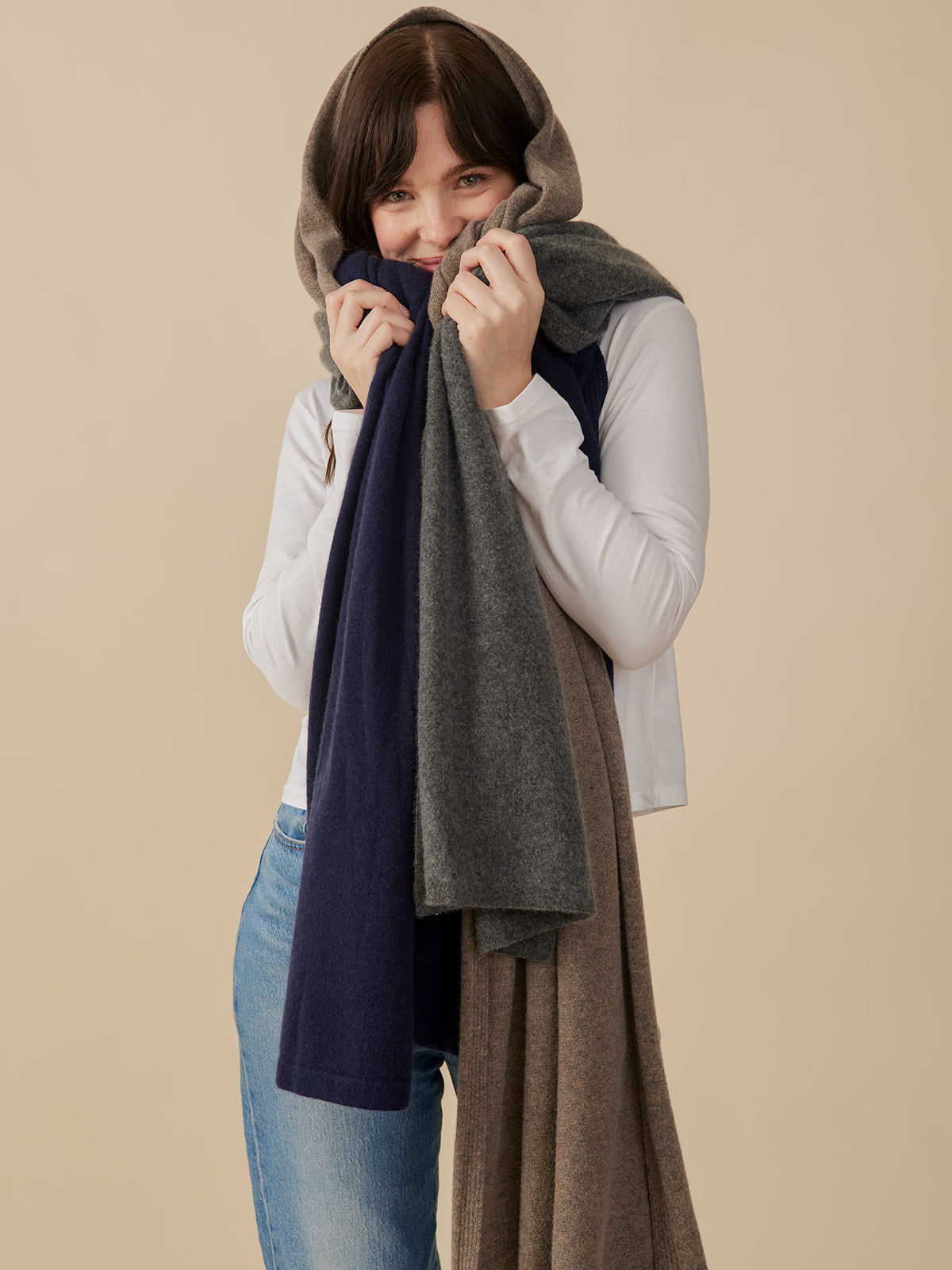 Woman wearing long, multicolored cashmere wrap scarves against a beige background - Mata Traders Slow Fashion Brand 