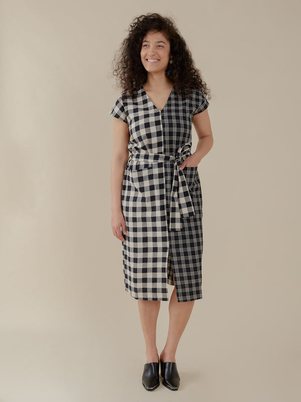 Woman wearing a black and white checkered dress against a beige background